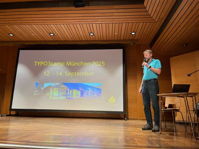 Speaker on stage in front of the screen with the date for 2025: September 12 to 14